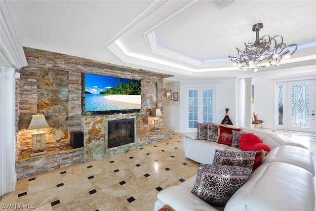 living room featuring tile patterned floors, a stone fireplace, an inviting chandelier, ornamental molding, and a raised ceiling