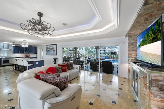 living room with a raised ceiling, an inviting chandelier, and ornamental molding