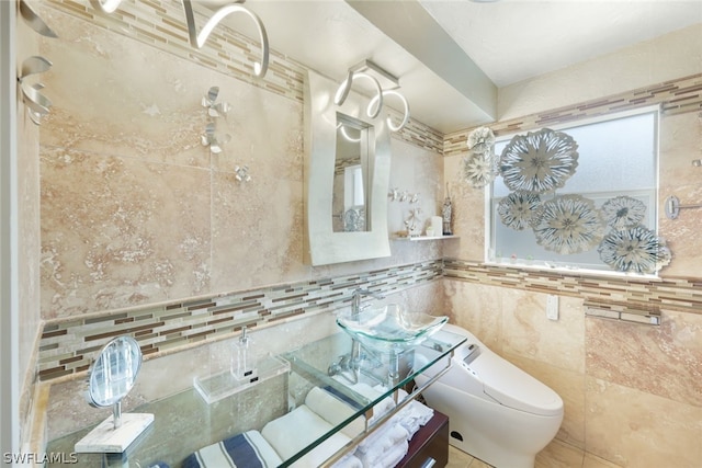 bathroom with toilet, tile walls, and sink