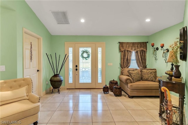 foyer with vaulted ceiling, light tile patterned flooring, and a healthy amount of sunlight