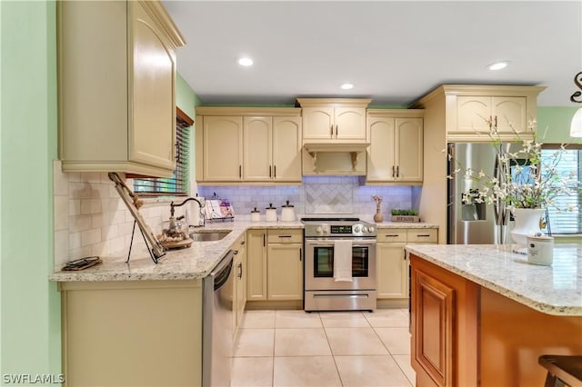 kitchen with light stone counters, stainless steel appliances, light tile patterned floors, and sink