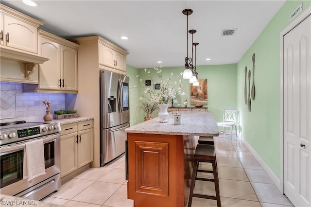 kitchen featuring stainless steel appliances, a center island, a kitchen breakfast bar, light tile patterned floors, and hanging light fixtures