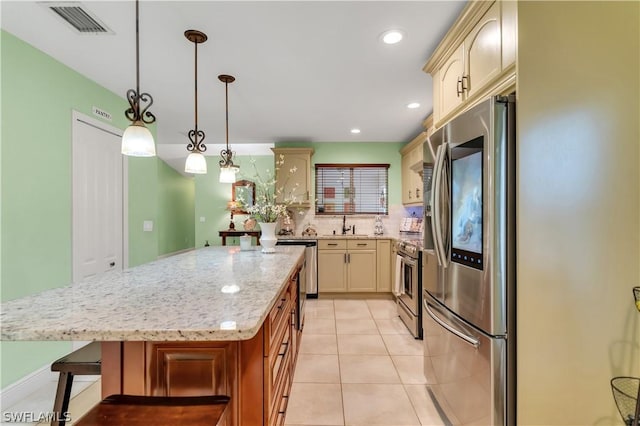 kitchen with appliances with stainless steel finishes, a center island, light stone counters, decorative backsplash, and light tile patterned flooring