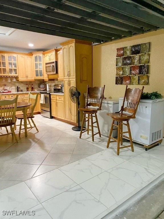 kitchen with stainless steel appliances, backsplash, and light brown cabinets