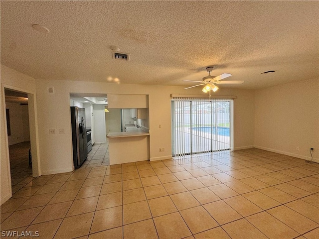 kitchen featuring stainless steel fridge, light tile patterned floors, a textured ceiling, and ceiling fan