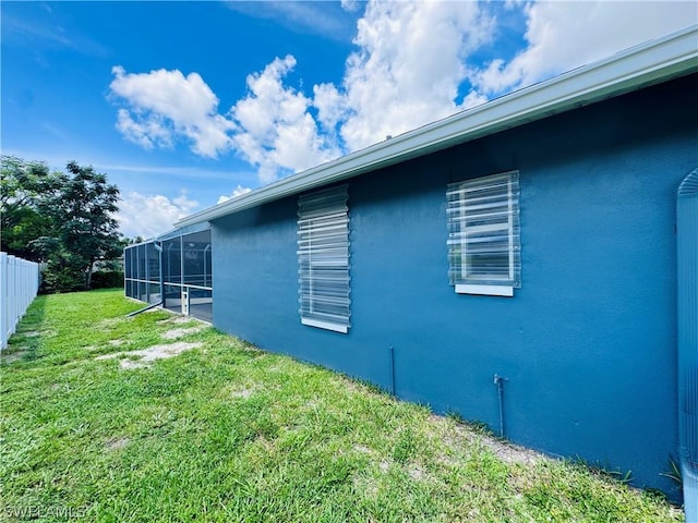 view of side of property with glass enclosure and a yard