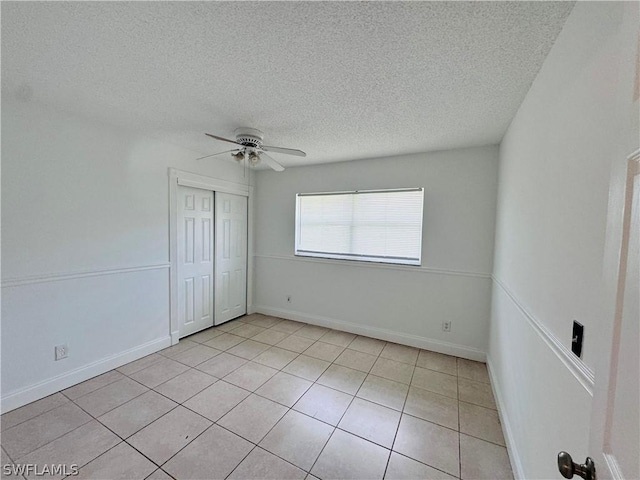 unfurnished bedroom with light tile patterned floors, a textured ceiling, a closet, and ceiling fan