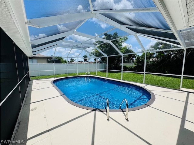 view of swimming pool with a yard, a patio, and a lanai