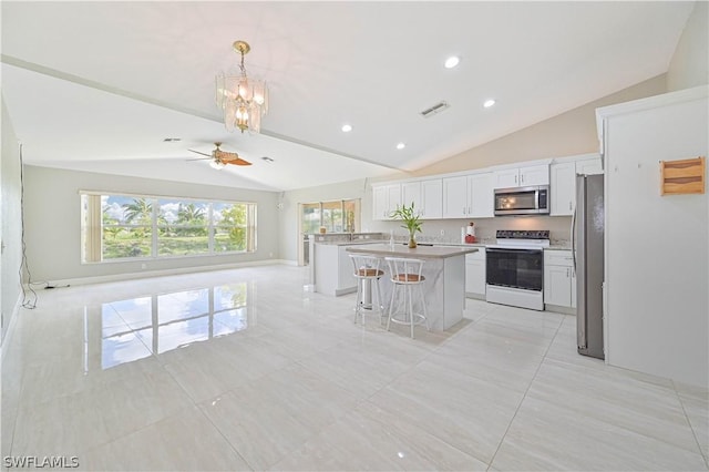 kitchen with a kitchen island, appliances with stainless steel finishes, decorative light fixtures, white cabinets, and a kitchen breakfast bar