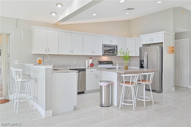 kitchen featuring a breakfast bar, sink, white cabinetry, vaulted ceiling, and stainless steel appliances