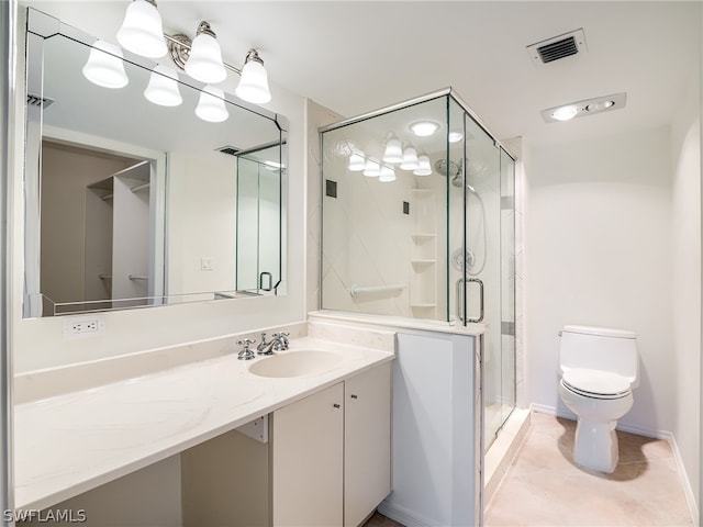 bathroom with a shower with shower door, vanity, tile patterned floors, and toilet