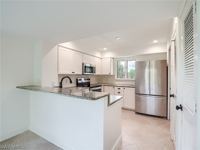 kitchen with kitchen peninsula, white cabinets, appliances with stainless steel finishes, decorative backsplash, and stone counters