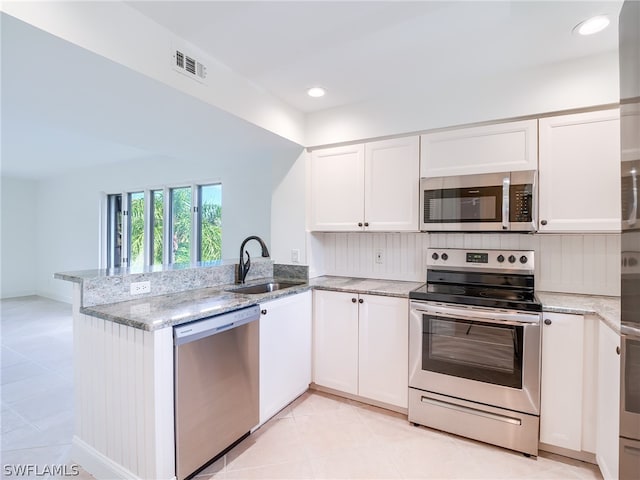 kitchen with stainless steel appliances, sink, kitchen peninsula, light stone counters, and light tile patterned flooring