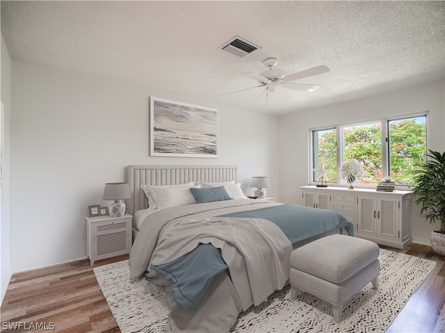 bedroom featuring a textured ceiling, light wood-type flooring, and ceiling fan