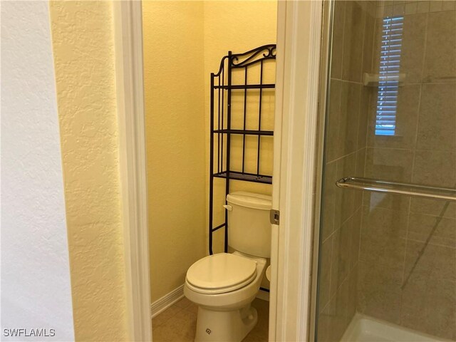 bathroom featuring tile patterned floors, toilet, and walk in shower