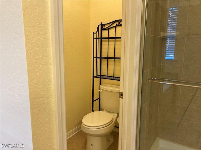 bathroom with toilet, tile patterned flooring, and a shower with door