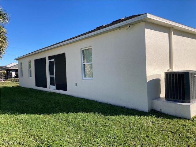 rear view of house with central AC and a lawn