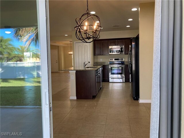 kitchen with light stone counters, dark brown cabinetry, stainless steel appliances, sink, and decorative light fixtures