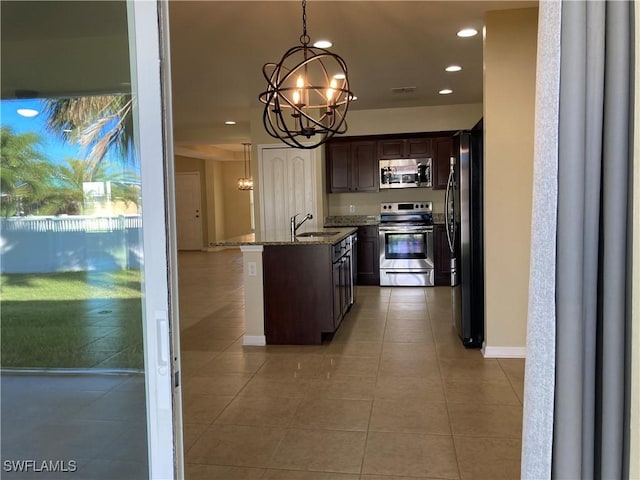 kitchen featuring pendant lighting, sink, stainless steel appliances, dark brown cabinetry, and light stone countertops