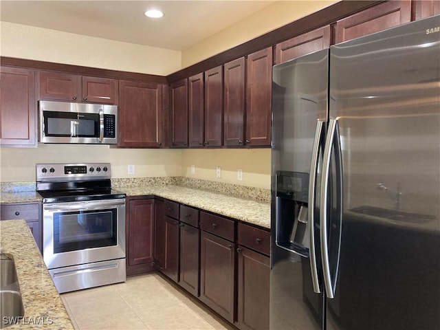 kitchen featuring light tile patterned floors, stainless steel appliances, and light stone counters