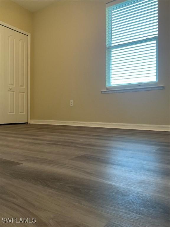 unfurnished bedroom featuring dark hardwood / wood-style flooring, a closet, and multiple windows