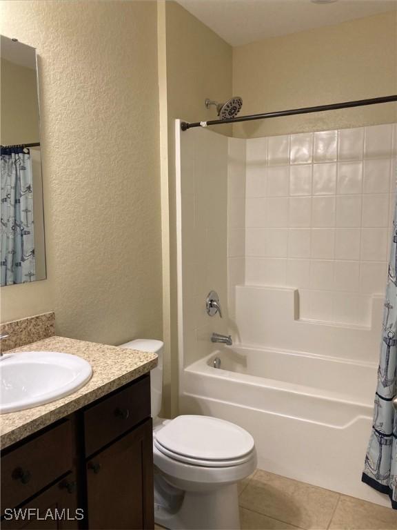 full bathroom featuring toilet, vanity, tile patterned floors, and shower / bath combo with shower curtain