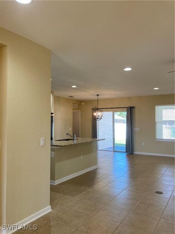 empty room featuring a wealth of natural light, light tile patterned flooring, and an inviting chandelier