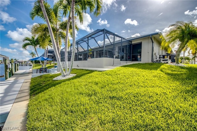 view of yard with a lanai, a boat dock, and a water view