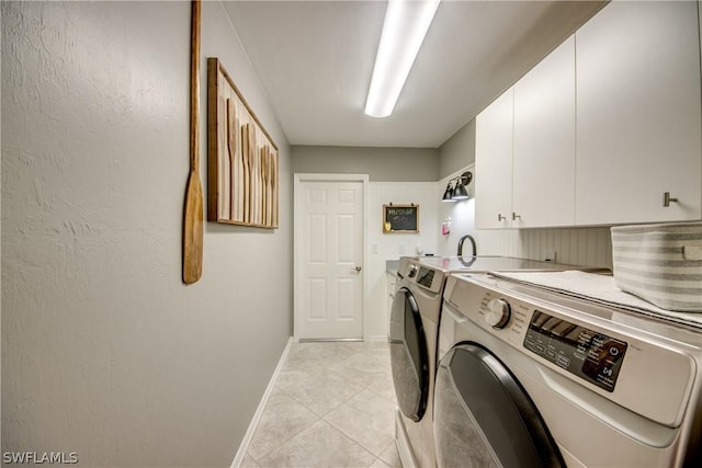 laundry area featuring washing machine and dryer, light tile patterned floors, and cabinets