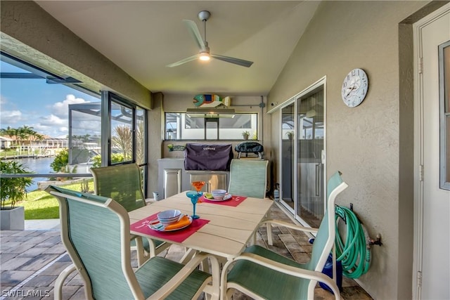 sunroom / solarium featuring ceiling fan, a water view, and lofted ceiling