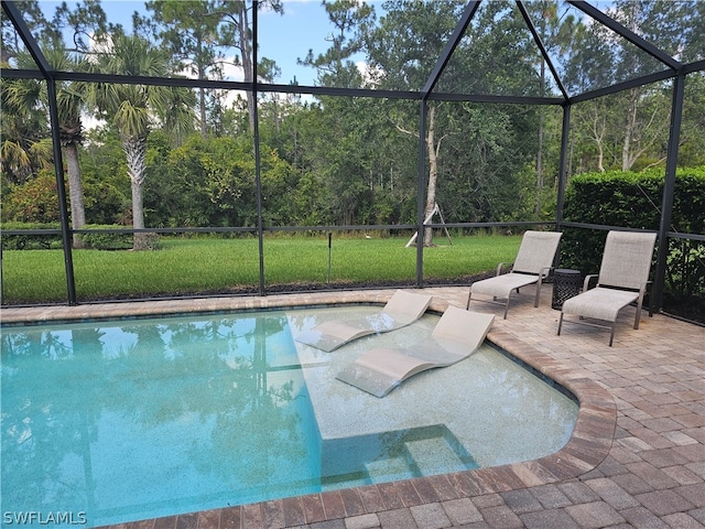 view of pool with glass enclosure and a patio area