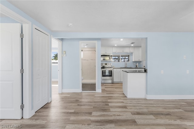 kitchen with white cabinetry, appliances with stainless steel finishes, a healthy amount of sunlight, and light hardwood / wood-style flooring