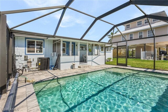 view of pool with central AC unit, glass enclosure, and a patio area