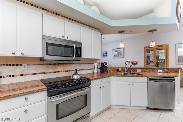 kitchen featuring white cabinets, decorative light fixtures, stainless steel appliances, dark stone countertops, and sink