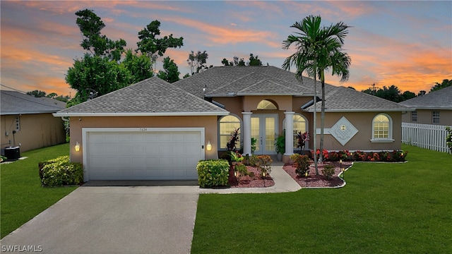 single story home featuring cooling unit, a garage, and a lawn