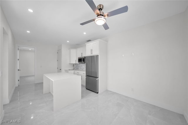 kitchen featuring appliances with stainless steel finishes, backsplash, a kitchen island, ceiling fan, and light tile patterned flooring