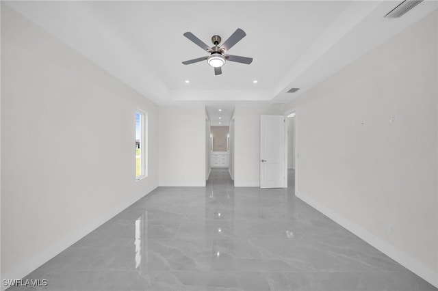 tiled spare room featuring ceiling fan and a raised ceiling