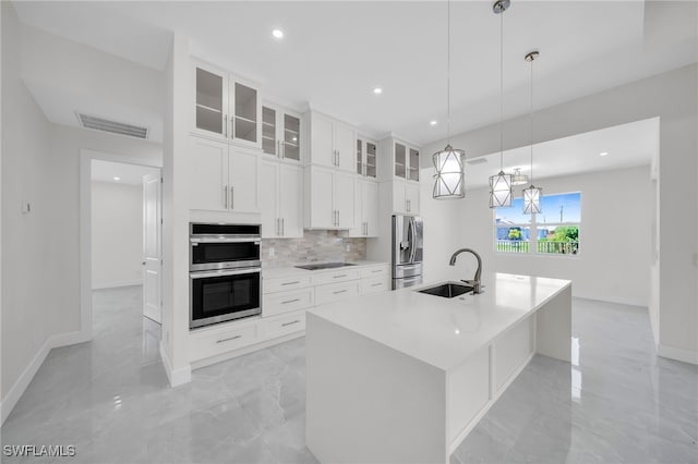 kitchen featuring backsplash, sink, appliances with stainless steel finishes, a kitchen island with sink, and pendant lighting