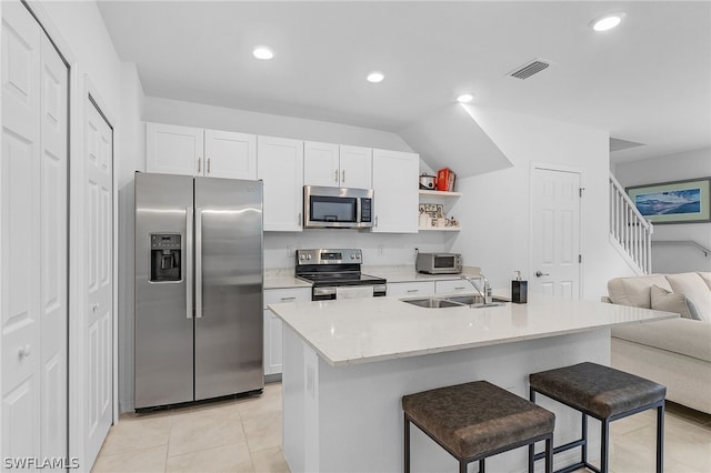 kitchen featuring sink, white cabinetry, appliances with stainless steel finishes, and an island with sink