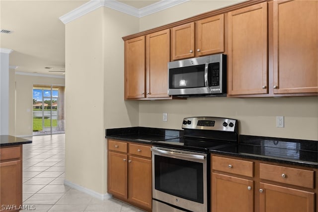 kitchen featuring light tile patterned flooring, dark stone countertops, crown molding, and appliances with stainless steel finishes