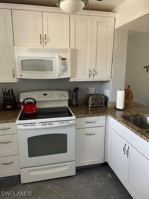 kitchen featuring white cabinetry, white appliances, and dark stone countertops