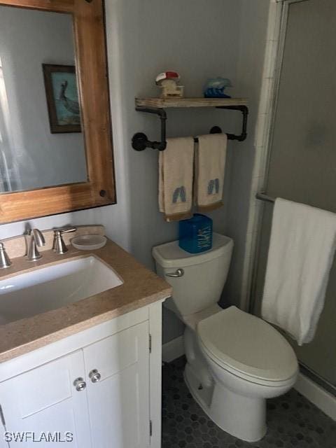 bathroom with vanity, tile patterned flooring, toilet, and walk in shower