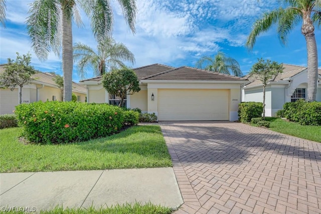 view of front of house featuring a garage, decorative driveway, a tile roof, and stucco siding