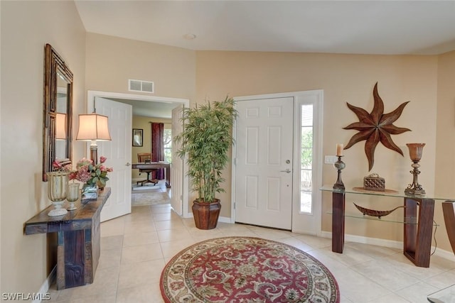 foyer featuring visible vents, vaulted ceiling, baseboards, and light tile patterned floors