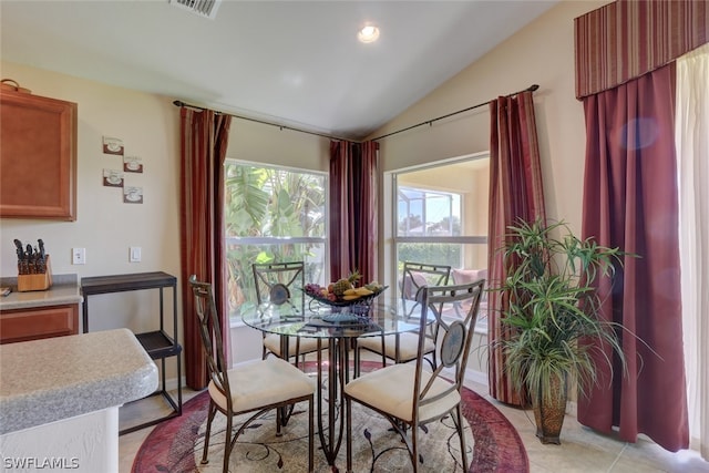 tiled dining room featuring vaulted ceiling