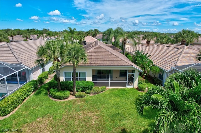 back of property with a lanai and a lawn