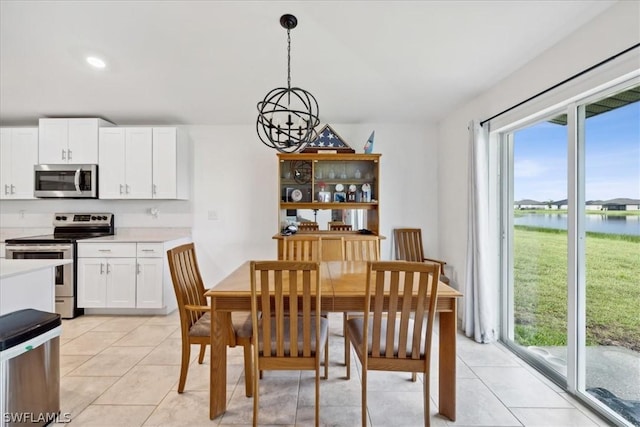 dining space featuring a water view, an inviting chandelier, and light tile patterned floors