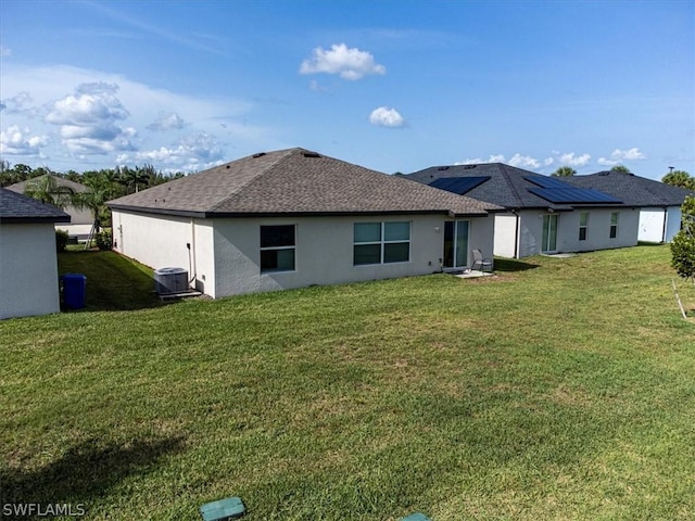 rear view of property featuring central AC unit and a lawn