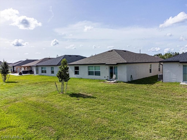 rear view of house with central AC unit and a lawn