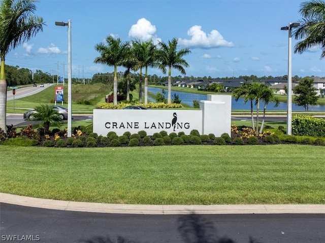 community sign with a water view and a lawn